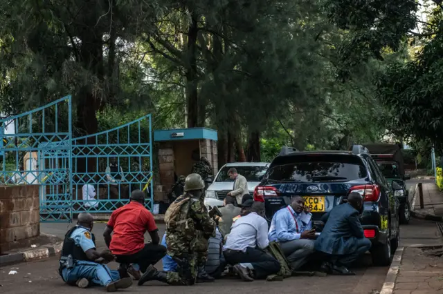 People hiding behind a car