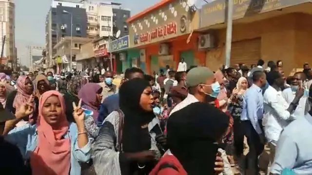 Men and women shout and gesticulate in a street protest in Sudan