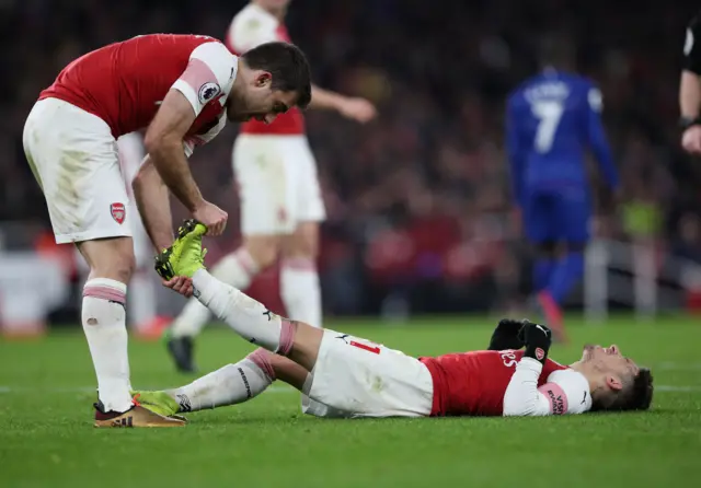 Arsenal"s Sokratis Papastathopoulos helps a cramp stricken Lucas Torreira