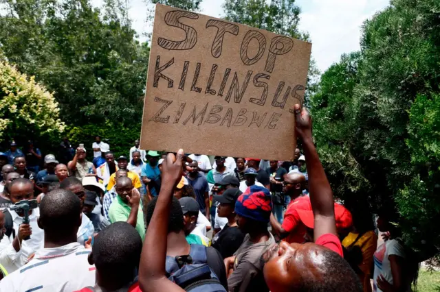 A protester holds a placard during a demonstration of Zimbabwean citizens outside the Zimbabwean Embassy in Pretoria