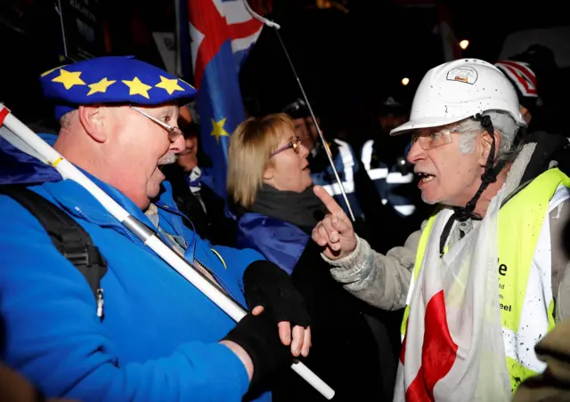 A pro-Brexit activist (R) wearing a "yellow vest" hi-vis jacket remonstsrates with an anthi-Brexit (L) activist as they demonstrate outside of the Houses of Parliament