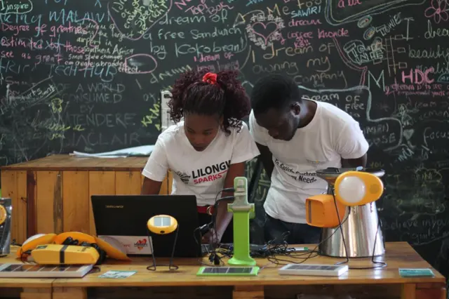 A man and a woman in a classroom looking at a computer