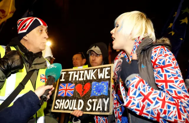 A pro-Brexit activist (L) wearing a "yellow vest" hi-vis jacket remonstrates with an anti-Brexit activist dressed in an Union flag-themed jacket, as they demonstrate outside of the Houses of Parliament