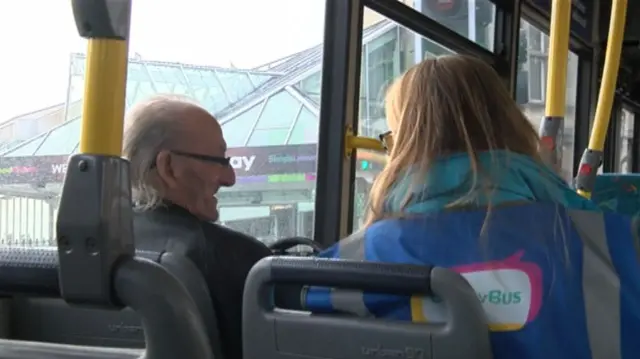 Two people talking on board a bus