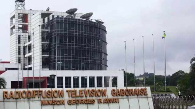 People walk past the premises of the National Radio and Television centre in Libreville, on June 16, 2017.