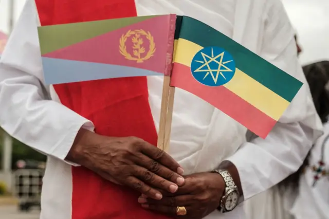 A man holds National flags of Eritrea (L) and Ethiopia