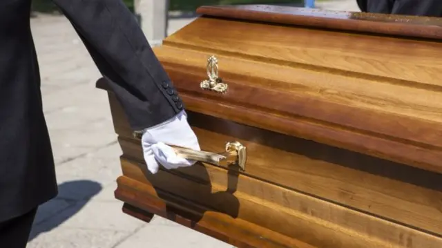 A generic shot of a coffin being held at the handle