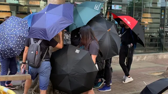 Protesters shield each other with umbrellas along the road in Hong Kong