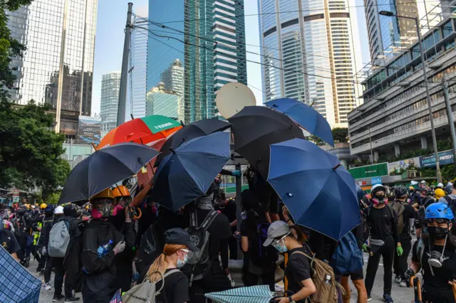 Protesters gather on a road with umbrellas