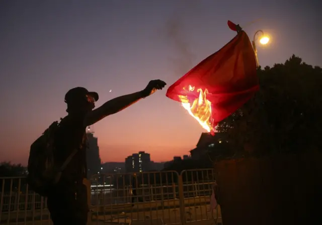 An anti-government demonstrator burns a Chinese national flag during a protest on National Day in Hong Kong