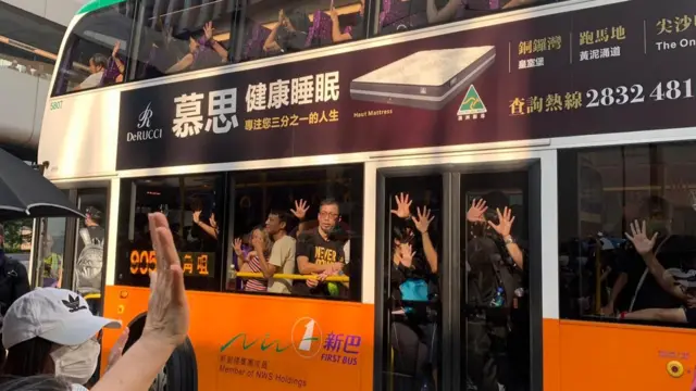 People place their hands on the windows of a bus passing by the protests in Hong Kong