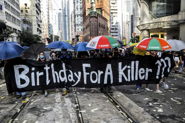 Anti-government protesters carry an anti-China banner