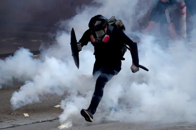 An anti-government protester runs through a cloud of tear gas during a protest in Sham Shui Po district, on China"s National Day in Hong Kong, China October 1, 2019