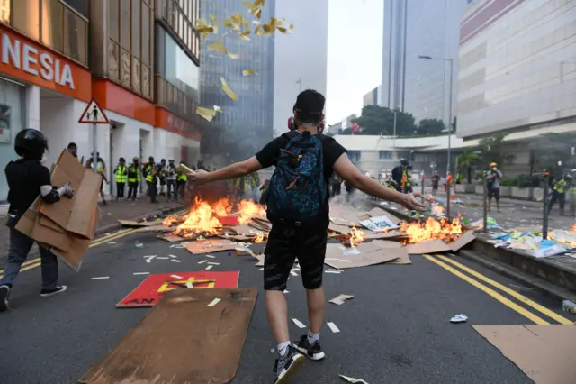 A protester throws ceremonial "joss paper", used in memory of those who died for democracy, into the air as a group set fire to debris