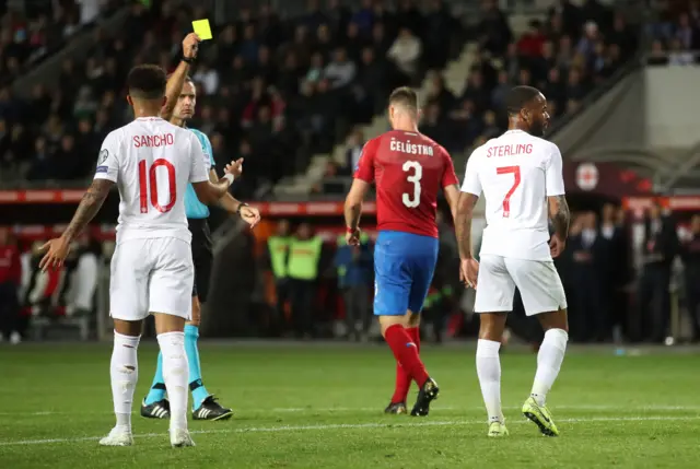 England's Raheem Sterling is shown a yellow card by referee Damir Skomina