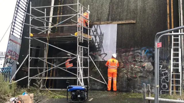 Workmen removing the mural