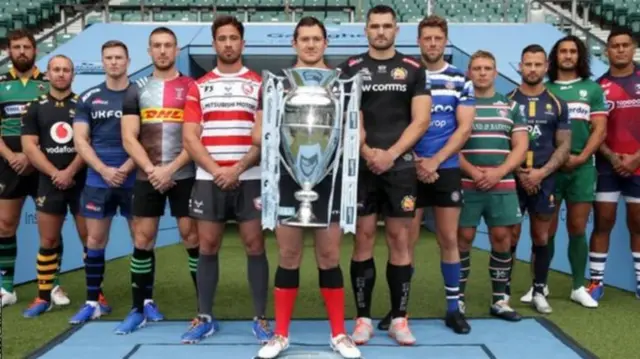 A player from each of the 12 clubs poses with the Premiership tophy