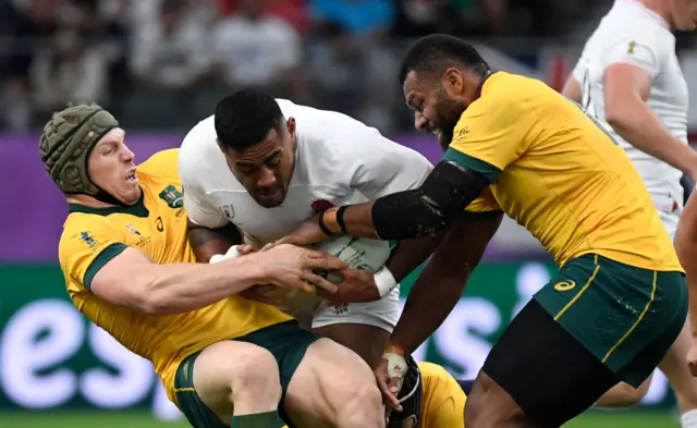 England's centre Manu Tuilagi (C) is tackled by Australia's flanker David Pocock (L) and Australia"s centre Samu Kerevi during the Japan 2019 Rugby World Cup quarter-final match between England and Australia at the Oita Stadium