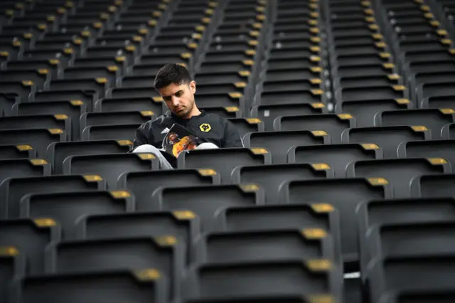 A fan reads the matchday programme