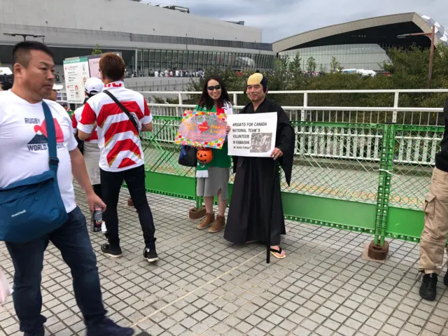 Two fans holding up signs saying thank you to Canada