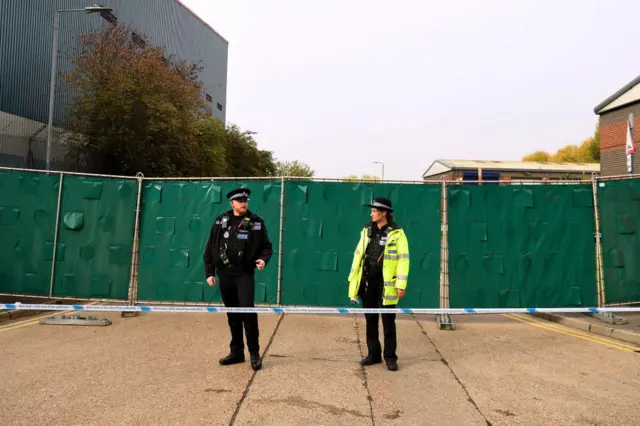 Two police officers next to a green barrier