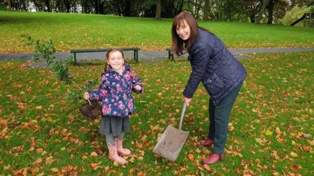 Child and councillor planting tree