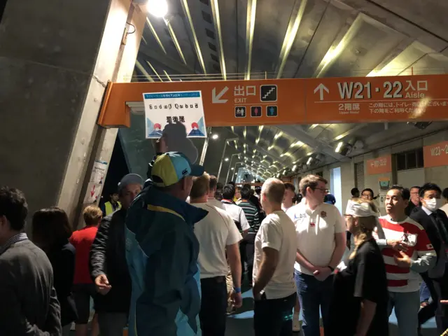 Volunteer holding up end of queue sign