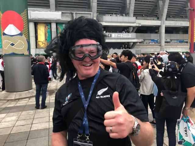 A man wearing a black wig and ski goggles