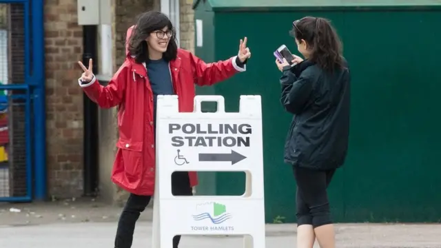 Young voters take photos next to a polling station sign