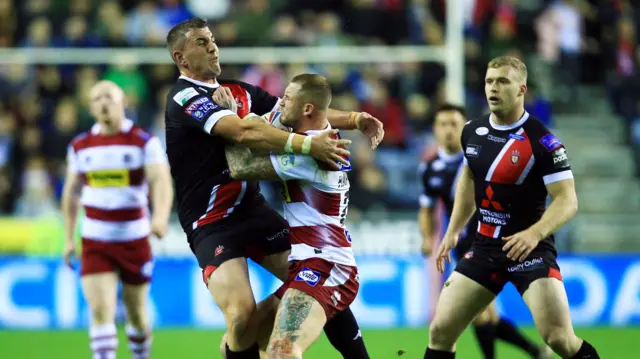 Zak Hardaker of Wigan Warriors is tackled by Adam Walker of Salford Red Devils