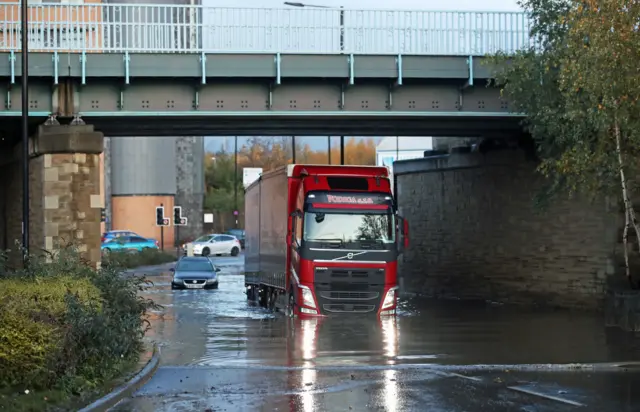 A lorry drives through floodwater near Meadowhall shopping centre in Sheffield where some people were forced to stay overnight after heavy rain and flooding caused local roads to become gridlocked