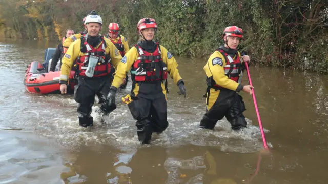 Firefighters walk through water