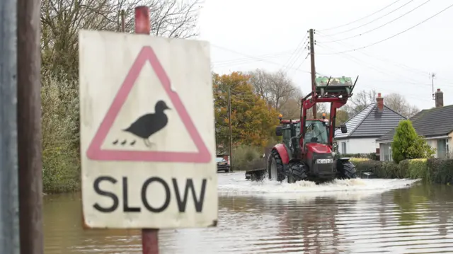 A tractor going through floodwater