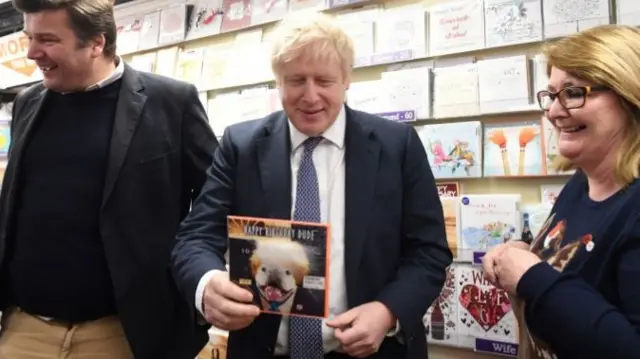 Prime Minister Boris Johnson holding a Boris Johnson birthday card in Scribbles greeting card shop, during a walkabout, in the Wells constituency, Somerset