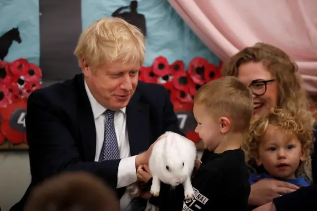 Boris Johnson holds a rabbit at a school