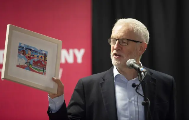 Jeremy Corbyn holds up a painting given to him by a local artist during a speech in Morecambe