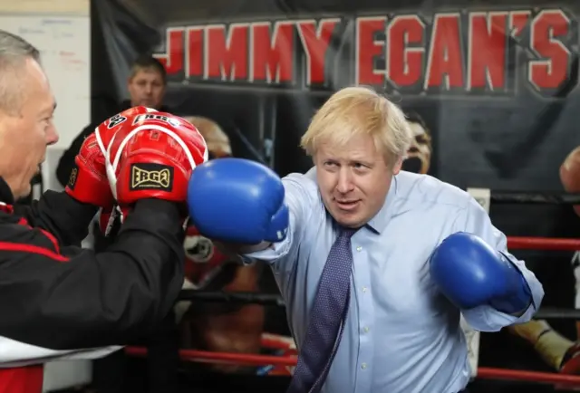 Boris Johnson poses for a photo wearing boxing gloves during a stop at Jimmy Egan"s Boxing Academy in Manchester, Britain November 19, 2019.