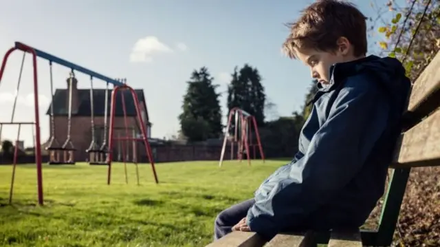 Child on bench by swings