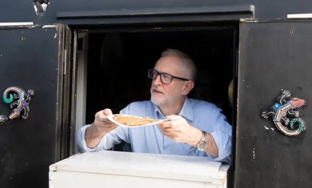 Jeremy Corbyn serves an oatcake from a canal boat in Stoke-on Trent