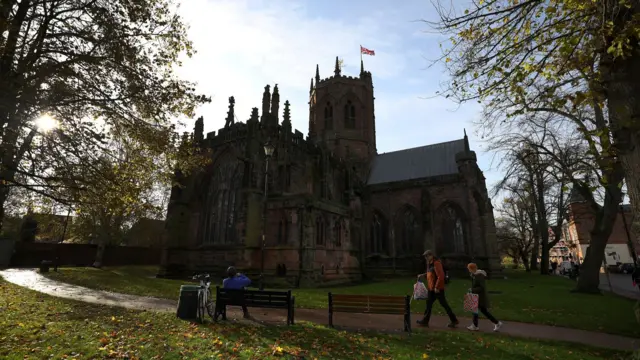 People walking past St Mary's Church in the centre of Nantwich