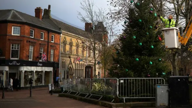 A council worker adds decorations to a Christmas tree in the town centre of Nantwich