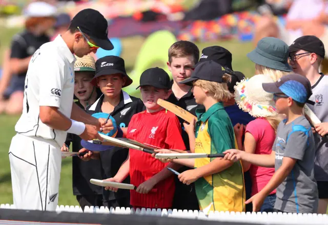 Trent Boult (L) signs autographs during the fourth day of the first cricket Test between England and New Zealand at Bay Oval in Mount Maunganui