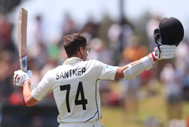 Mitchell Santner celebrates after reaching his century during the fourth day of the first Test cricket match between England and New Zealand at Bay Oval in Mount Maunganui