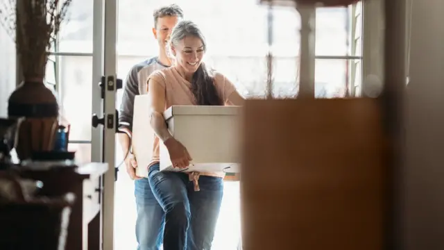 People carrying a box into a house