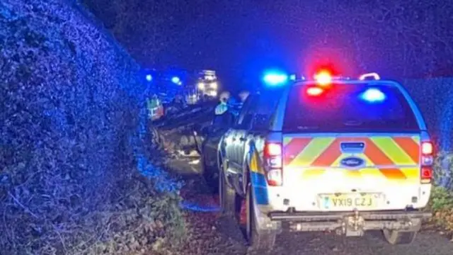 Car on roof behind emergency vehicle