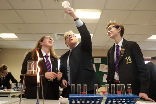 Britain's Prime Minister and Conservative Party leader, Boris Johnson (C), helps Year-11 Head Girl Ruby Culter (L) and Head Boy Matthew Upright (R) with a science experiment as he visits Chulmleigh College while campaigning for the general election in Chulmleigh, Devon