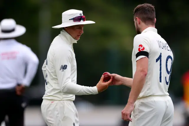 Joe Root (L) gives instructions to teammate Chris Woakes as he gets ready to bowl on day one of the second cricket Test between England and New Zealand at Seddon Park