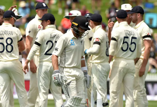 New Zealand's batsman Kane Williamson (C) walks back to the pavilion as England players celebtrate his dismissal on day one of the second cricket Test between England and New Zealand at Seddon Park