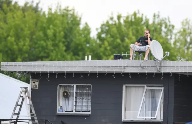 New Zealand fan watches the game from the roof of a house