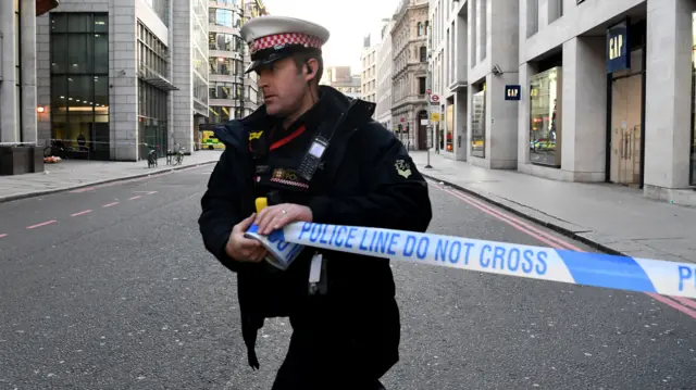 Police officer putting across cordon tape